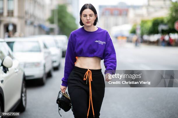 Maria Barteczko wearing purple printed croped sweater MIAM-IAM, black logo track pants MIA-IAM, black sock boots Stuart Weitzman, black leather...