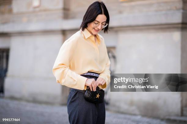 Maria Barteczko wearing light yellow silk blouse The Row, grey logo wide leg trousers Celine, yellow buckle slipper Mango, black leather belt bag...