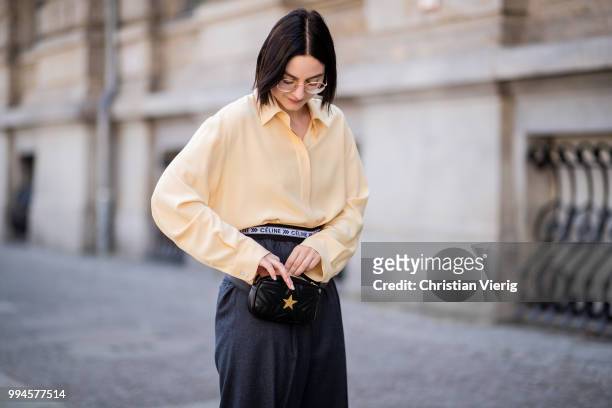 Maria Barteczko wearing light yellow silk blouse The Row, grey logo wide leg trousers Celine, yellow buckle slipper Mango, black leather belt bag...