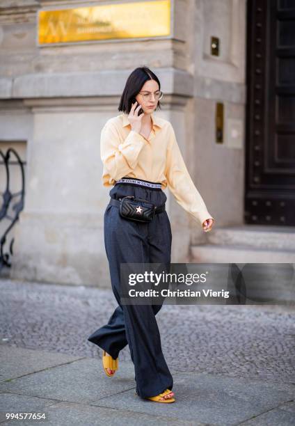 Maria Barteczko wearing light yellow silk blouse The Row, grey logo wide leg trousers Celine, yellow buckle slipper Mango, black leather belt bag...