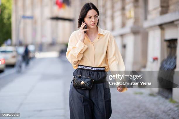 Maria Barteczko wearing light yellow silk blouse The Row, grey logo wide leg trousers Celine, yellow buckle slipper Mango, black leather belt bag...