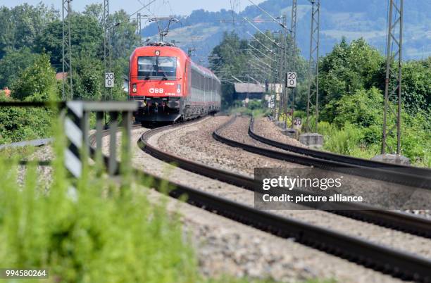 July 2018, Germany, Flintsbach Am Inn: A train of the Austrian Federal Railways driving over the tracks of the Bahntrasse through the valley of the...