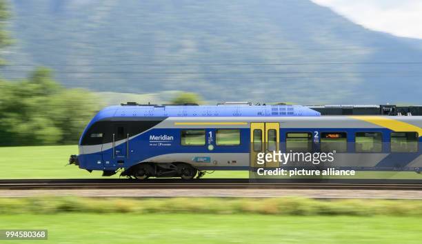 July 2018, Germany, Flintsbach Am Inn: A train of the Austrian Federal Railways driving over the tracks of the Bahntrasse through the valley of the...