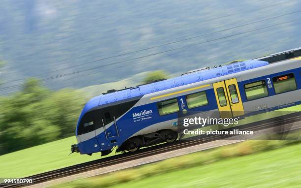 July 2018, Germany, Flintsbach Am Inn: A train of the Austrian Federal Railways driving over the tracks of the Bahntrasse through the valley of the...