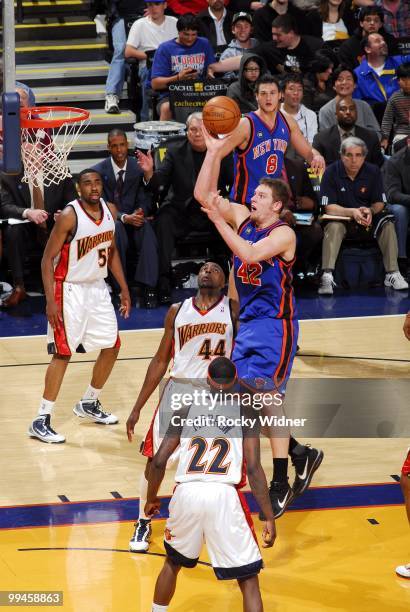 David Lee of the New York Knicks goes up for a shot against Anthony Tolliver and Anthony Morrow of the Golden State Warriors during the game at...