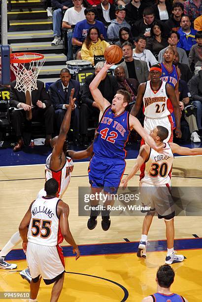 David Lee of the New York Knicks goes up for a shot against Anthony Tolliver, Reggie Williams and Stephen Curry of the Golden State Warriors during...