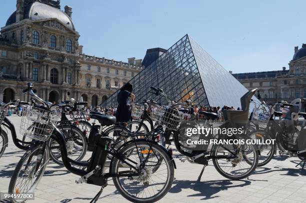 Picture taken on July 9, 2018 shows electric bikes in front of the Pyramide du Louvre in Paris.