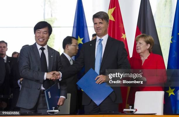 Yumin Qi, chief executive officer of Brilliance China Automotive, left, shakes hands with Harald Krueger, chief executive officer of Bayerische...