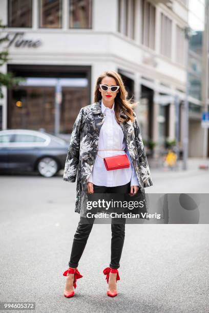 Alexandra Lapp wearing a long blazer jacket with floral prints in green, white and gold tones from Steffen Schraut, a white long shirt and slim...