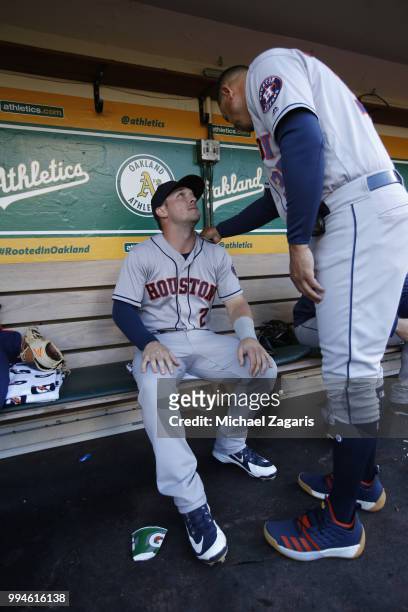 Alex Bregman and First Base Coach Alex Cintron of the Houston Astros talk in the dugout prior to the game against the Oakland Athletics at the...