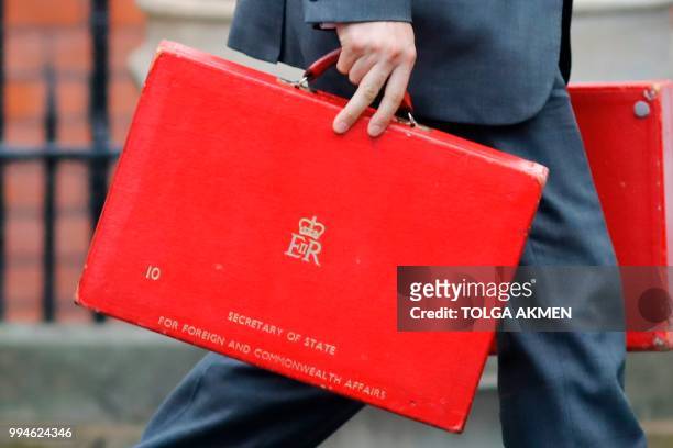 Member of a security team carries ministerial red boxes of the British Foreign Secretary to a car to be driven away from the official residence of...