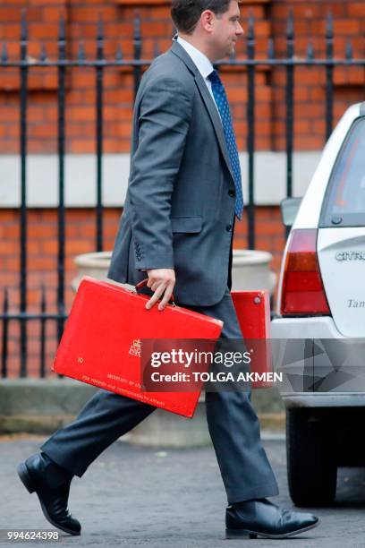 Member of a security team carries ministerial red boxes of the British Foreign Secretary to a car to be driven away from the official residence of...