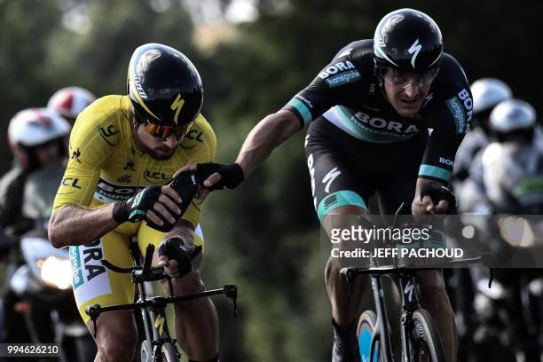 Germany's Marcus Burghardt handa a water bottle to Slovakia's Peter Sagan, wearing the overall leader's yellow jersey, during the third stage of the...
