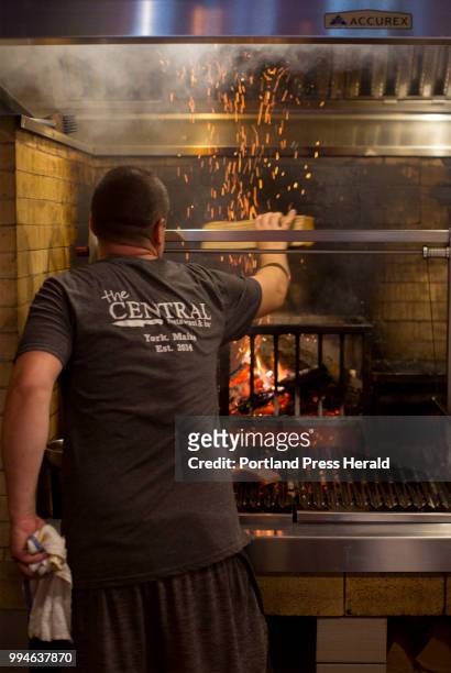 Merrill Sargent, the grill cook at The Central Restaurant + Bar, adds another log to the wood fired berth grill that was custom made for the...