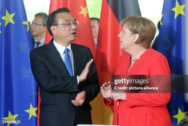 July 2018, Germany, Berlin: German Chancellor Angela Merkel of the Christian Democratic Union and China's Premier Li Keqiang in conversation during...