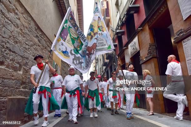 Revelers walk on the street during the San Fermin bull run festival in Pamplona, northern Spain on July 9, 2018 - Each day at 8am hundreds of people...