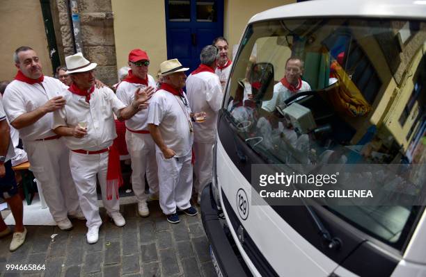 Revelers walk on the street during the San Fermin bull run festival in Pamplona, northern Spain on July 9, 2018 - Each day at 8am hundreds of people...
