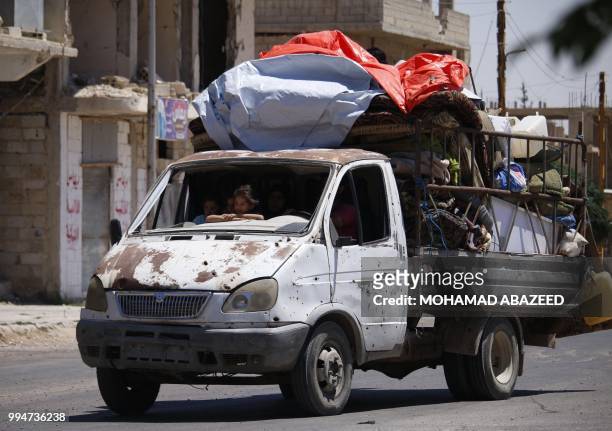 Syrians ride in a loaded vehicle return to their homes in towns and villages in the eastern outskirts of Daraa on July 9, 2018. The Syrian regime...