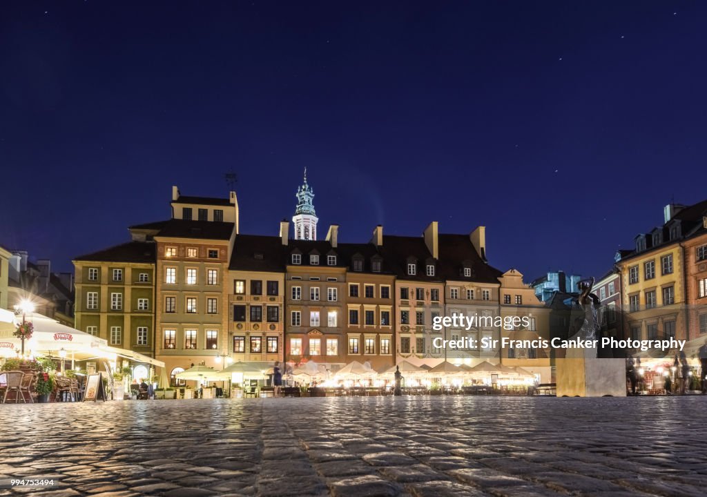 Medieval Rynek square (Market square) with colorful houses illuminated at night in Warsaw, Poland