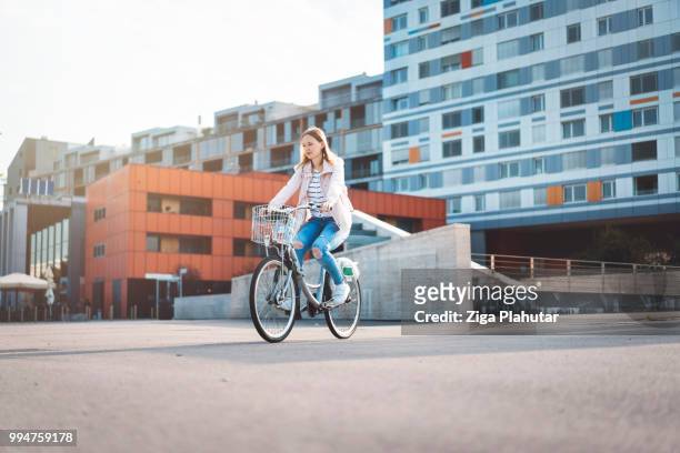 young girl with bicycle is enjoying the sunset in town - three wheeled vehicle stock pictures, royalty-free photos & images