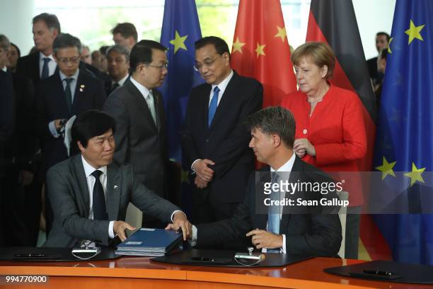 Chinese Premier Li Keqiang and German Chancellor Angela Merkel look on as Qi Yumin , Chairman of Chinese automaker Brilliance, and BMW Chairman...