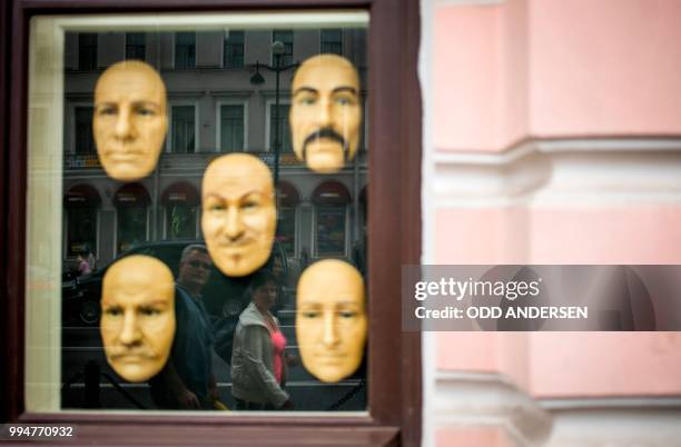 People and traffic along the Nevsky Prospect is refclected in the window of a mask museum in St. Petersburg on July 9 on the eve of the Russia 2018...