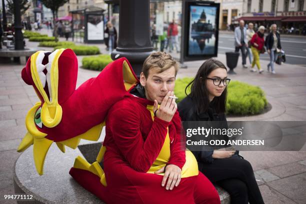 Man dressed up as a dragon for advertising purposes have a cigarette break on Nevsky Prospect in St. Petersburg on July 9 on the eve of the Russia...