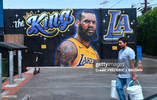 Man walks by a mural of LeBron James in a Los Angeles Lakers jersey in Venice, California on July 9, 2018. - It was originally revealed July 6 and...