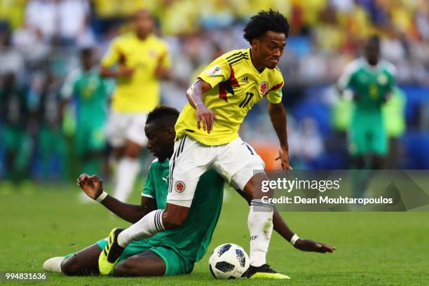 Juan Cuadrado of Colombia is challenged by Salif Sane of Senegal during the 2018 FIFA World Cup Russia group H match between Senegal and Colombia at...