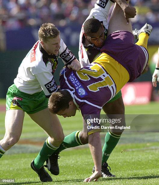 Dane Carlaw of Brisbane is up ended in a tackle by Brett Finch and Ken Nagas of Canberra during the NRL round 25 match between the Brisbane Broncos...