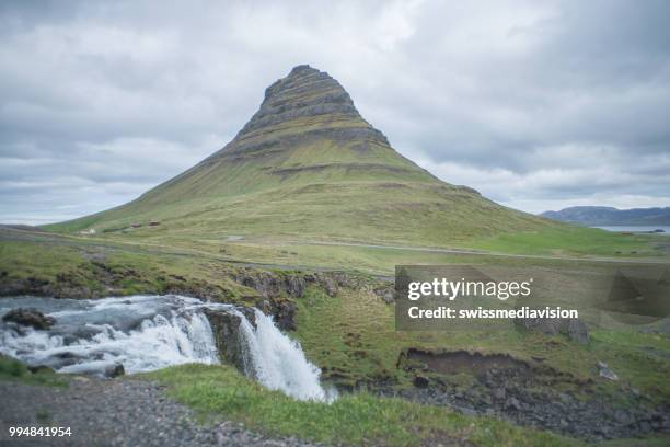 avec cascade kirkjufellsfoss en islande contre ciel couvert, aucun peuple spectaculaire montagne kirkjufell - islande du centre ouest photos et images de collection