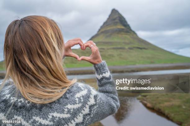 jeune femme en islande faire coeur forme doigt cadre au célèbre mont kirkjufell - islande du centre ouest photos et images de collection