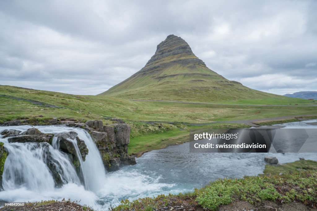 Spectaculaire Kirkjufell berg en waterval Kirkjufellsfoss in IJsland tegen bewolkte hemel, geen mensen