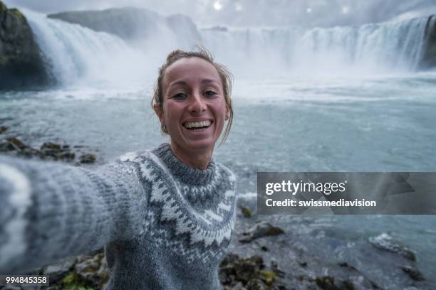 jonge vrouw portretje van de selfie met prachtige waterval in ijsland, godafoss valt. mensen reizen exploratie concept - northeast iceland stockfoto's en -beelden