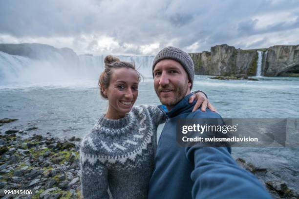 paar portretje van de selfie met prachtige waterval in ijsland, valt godafoss. mensen reizen exploratie concept - northeast iceland stockfoto's en -beelden