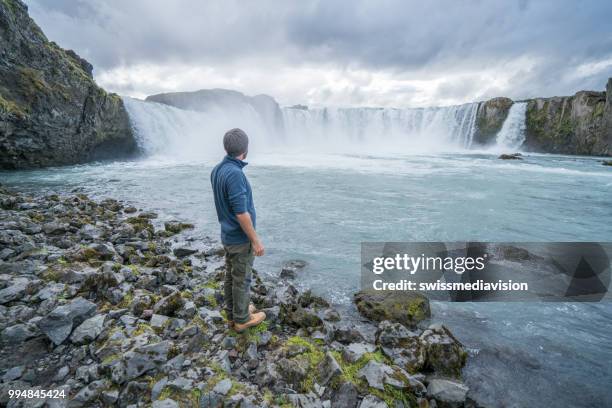jonge man overweegt waterval in ijsland - northeast iceland stockfoto's en -beelden