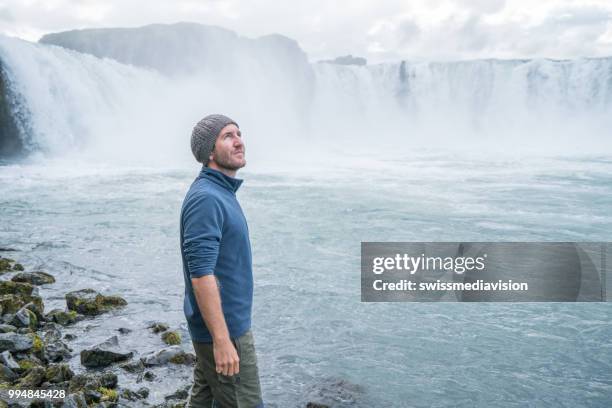 jonge man overweegt waterval in ijsland - northeast iceland stockfoto's en -beelden