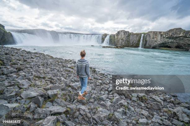 jonge vrouw dwalen in de buurt van de waterval in ijsland - northeast iceland stockfoto's en -beelden