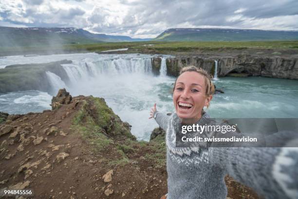 jonge vrouw portretje van de selfie op de top van prachtige waterval in ijsland, godafoss valt. mensen reizen exploratie concept - northeast iceland stockfoto's en -beelden