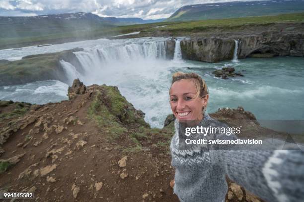 jonge vrouw portretje van de selfie op de top van prachtige waterval in ijsland, godafoss valt. mensen reizen exploratie concept - northeast iceland stockfoto's en -beelden
