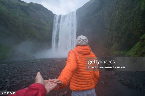 follow me to the waterfall, girlfriend leading man to godafoss falls in iceland - follow me stock pictures, royalty-free photos & images