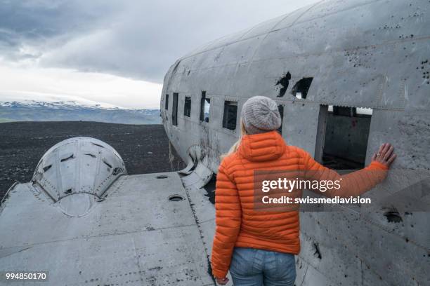 jeune femme se dresse en avion s’est écrasée sur la plage de sable noir en parcourant son entourage envisage - swissmediavision photos et images de collection