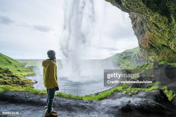 touristischen weibliche reisen in island in der nähe von herrlichen wasserfall steht und betrachtet die natur, die leute reisen abenteuer-konzept - swissmediavision stock-fotos und bilder