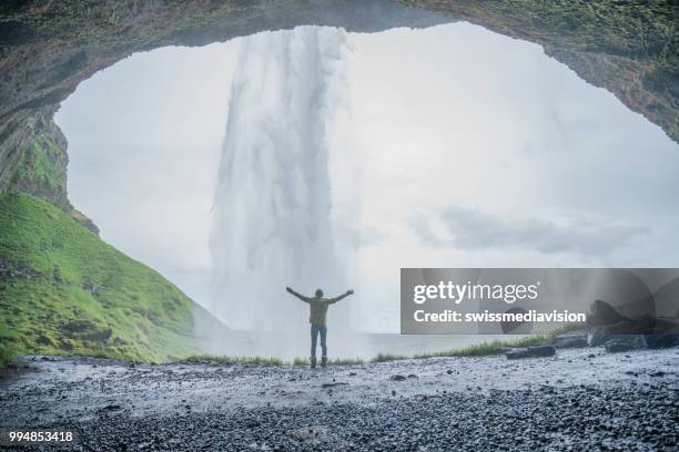 bras de jeune femme étendus derrière une chute d’eau spectaculaire en islande - swissmediavision photos et images de collection