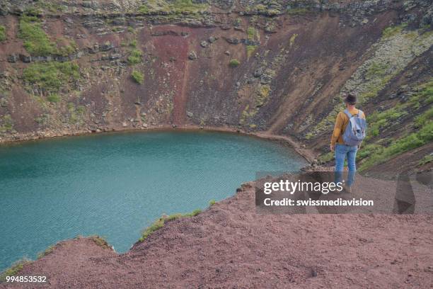 junger mann in island betrachtung kratersee von oben drauf - swissmediavision stock-fotos und bilder