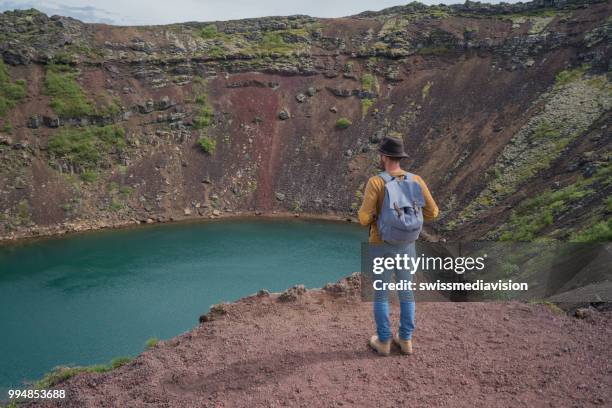 junger mann in island betrachtung kratersee von oben drauf - swissmediavision stock-fotos und bilder