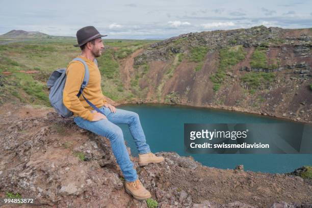 junger mann in island betrachtung kratersee von oben drauf - swissmediavision stock-fotos und bilder