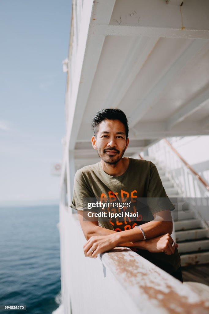 Portrait of Japanese man smiling at camera on ferry deck