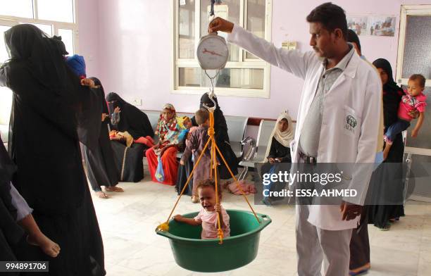 Displaced Yemeni child from the city of Hodeidah is weighed at a clinic in the northern district of Yemen's Hajjah province on July 9, 2018. - The...