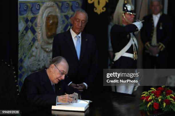 Portugal's President Marcelo Rebelo de Sousa looks to Prince Karim Aga Khan IV as he signs the honor book during an official visit at the Belem...